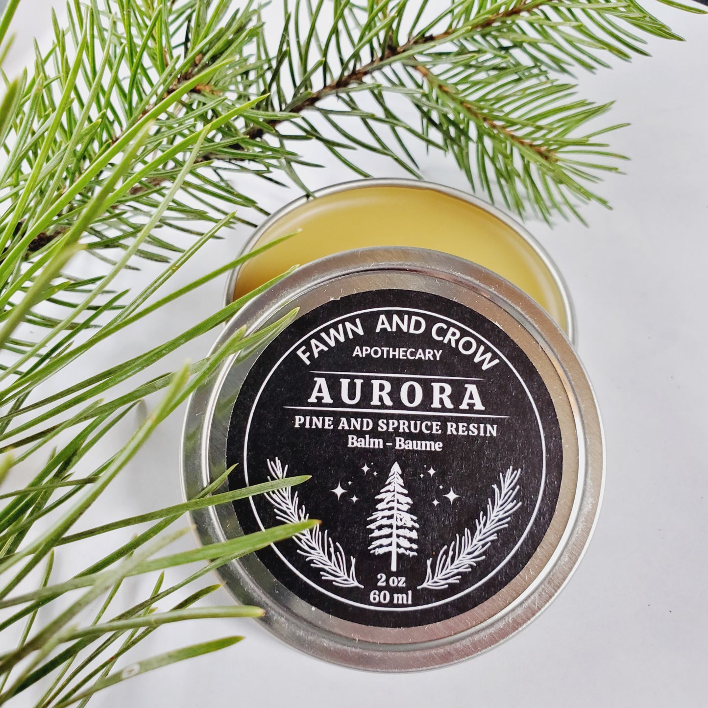 Fawn and Crow Apothecary Aurora balm with pine and spruce needles in background