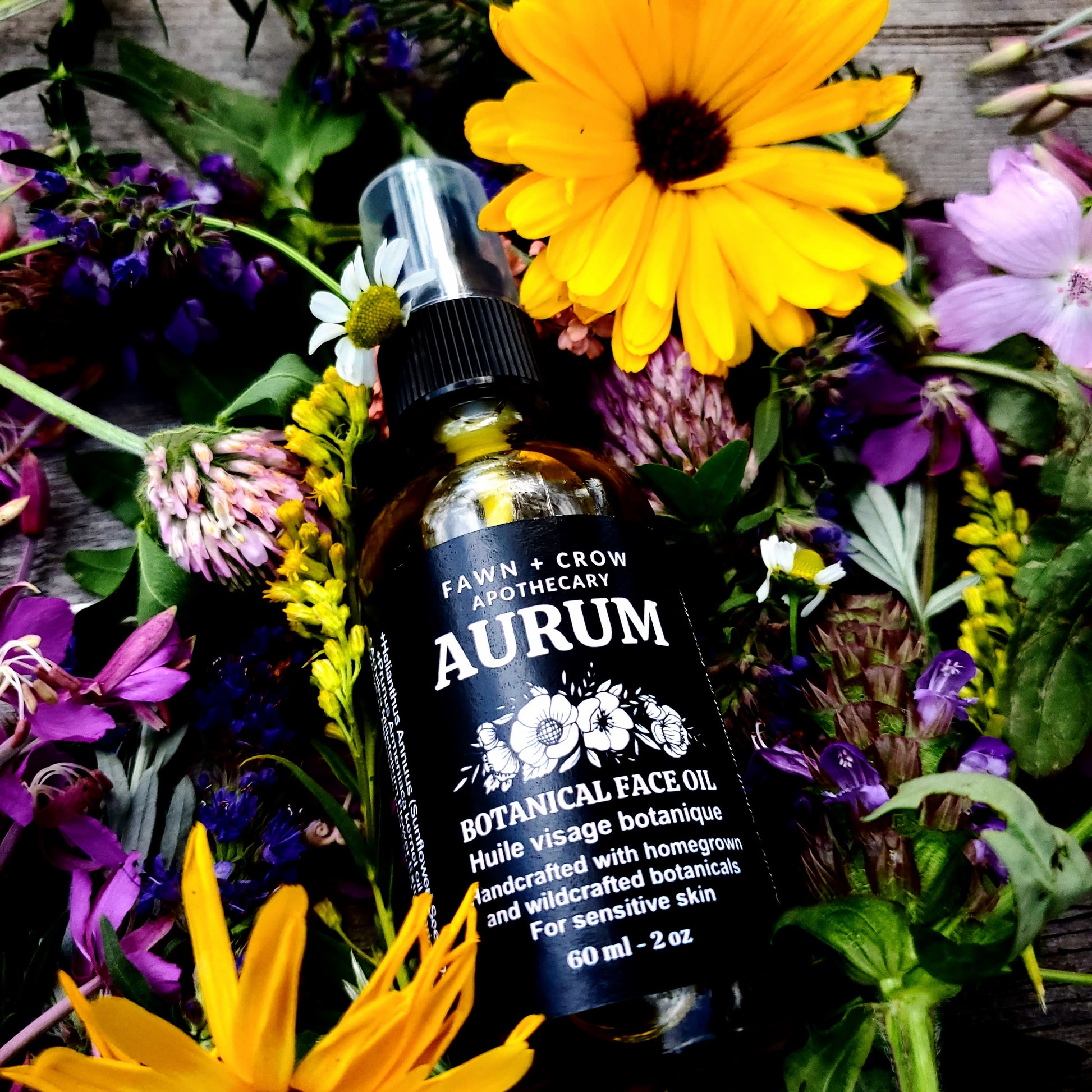 Aurum botanical face oil bottle surrounded by wildflowers on a wooden surface