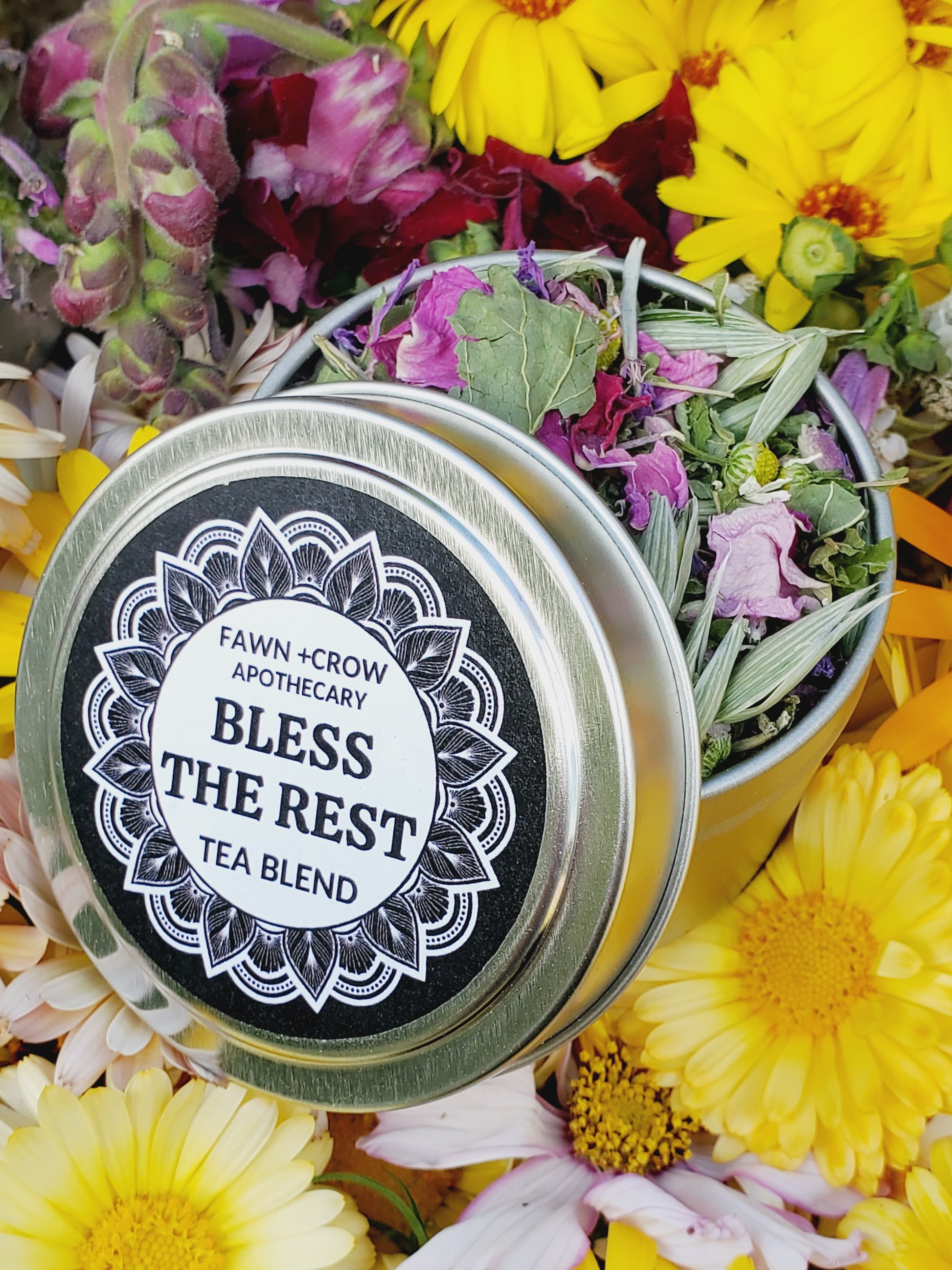 Herbal tea blend in a silver tin surrounded by flowers