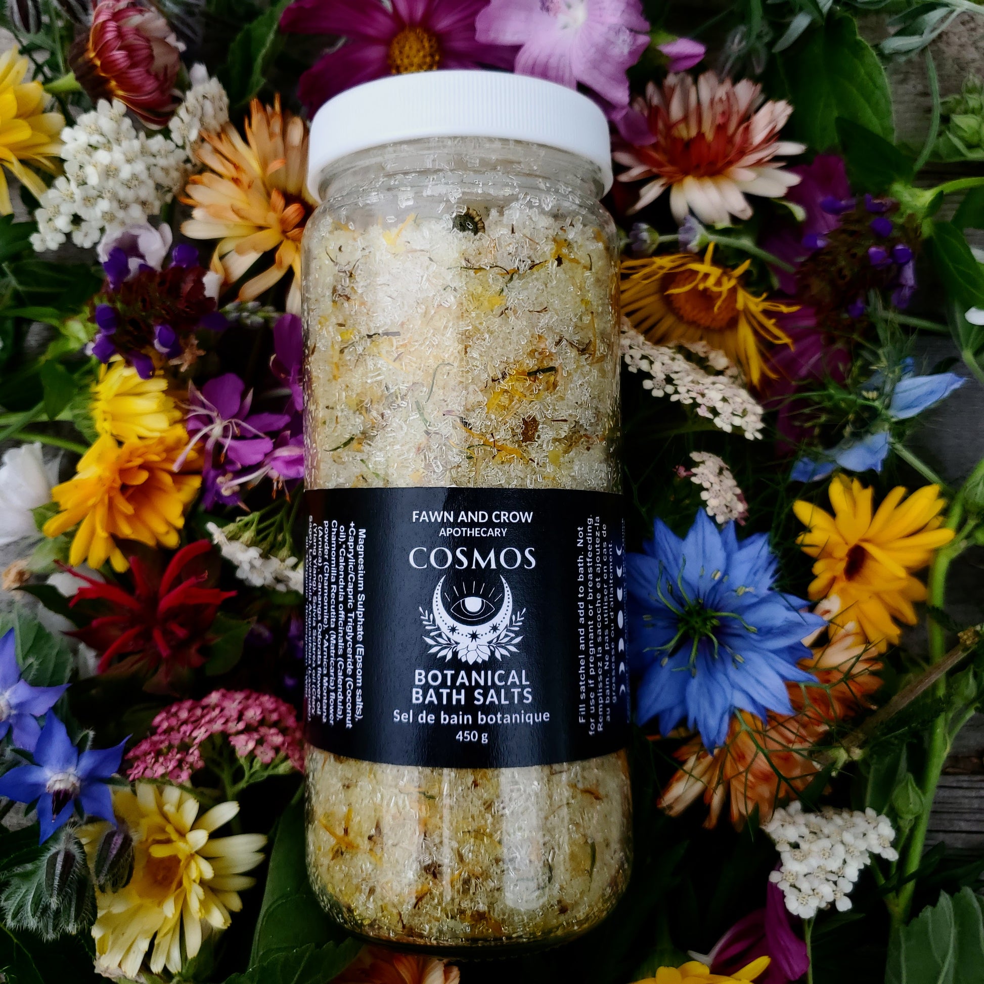 Jar of Cosmos Bath soak salts by Fawn and Crow Apothecary surrounded by colorful flowers