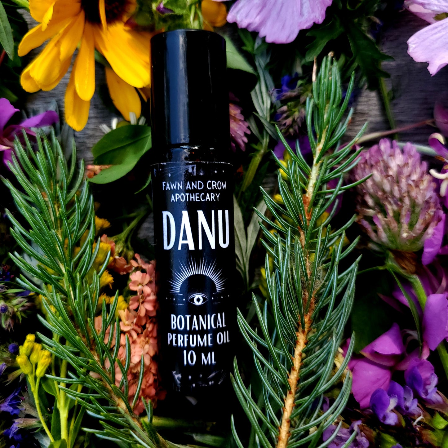 DANU perfume oil bottle surrounded by flowers and greenery