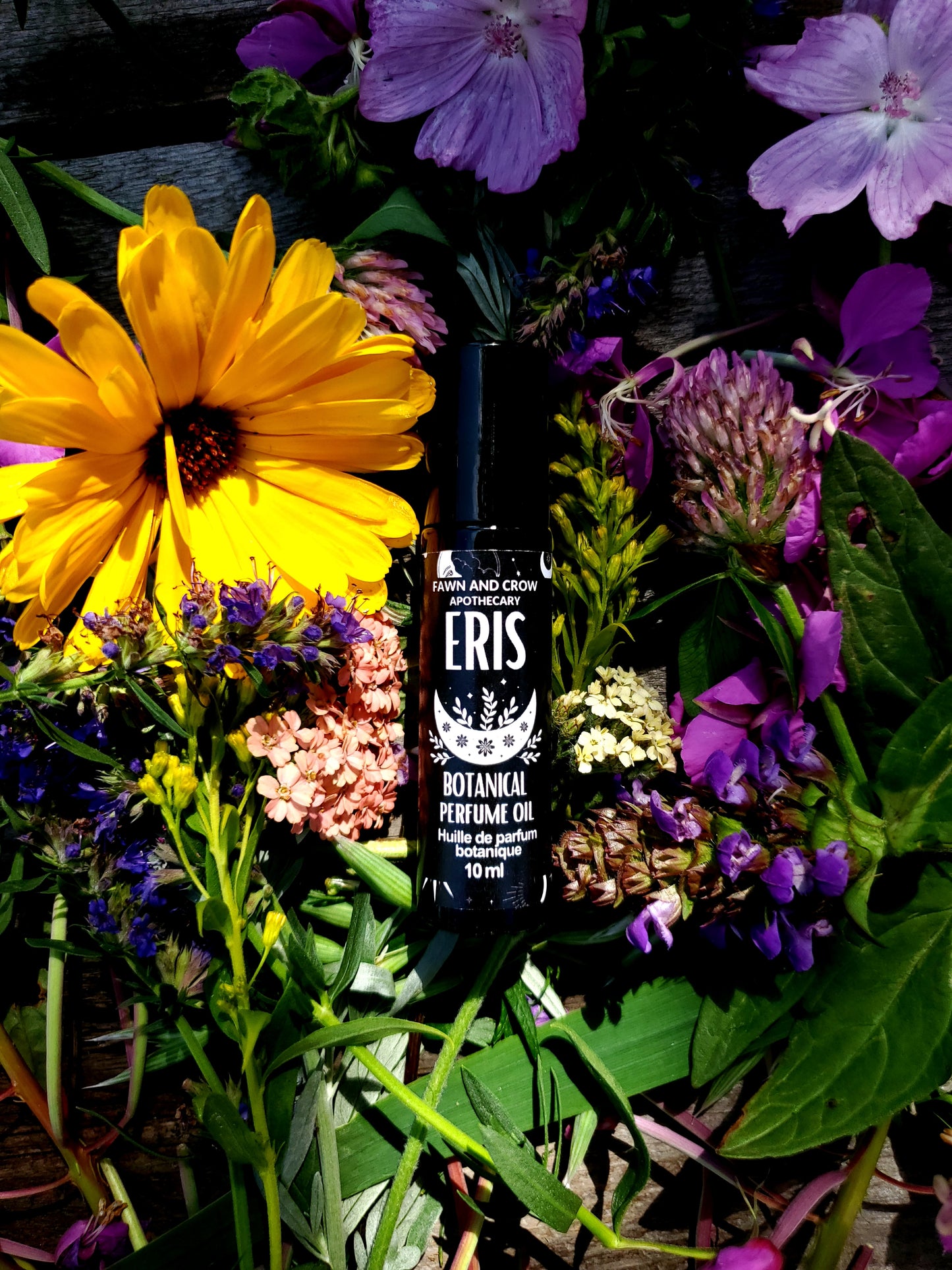 Bottle of Eris Perfume oil on a bed of flowers