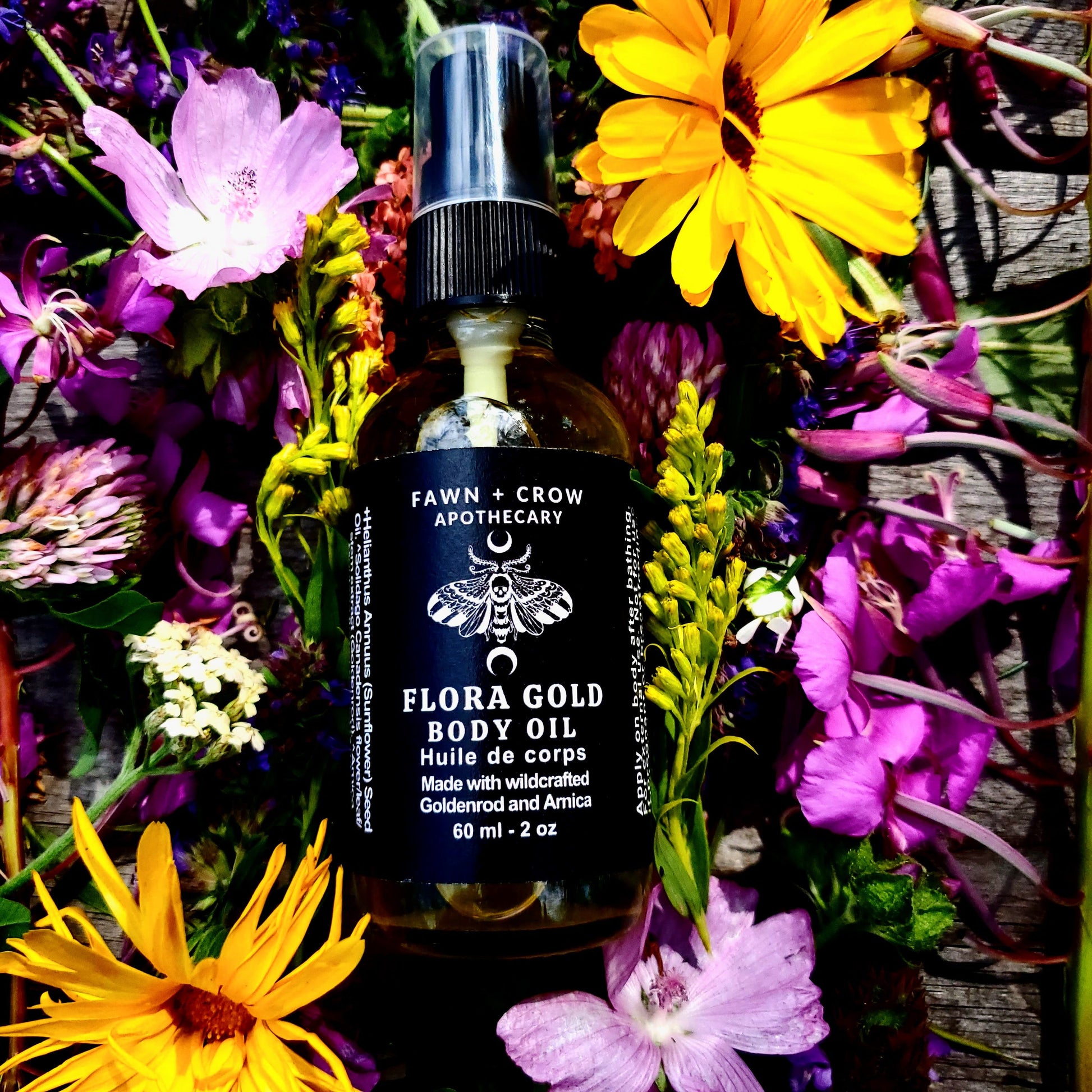 Bottle of Fawn + Crow Apothecary Flora Gold Body Oil surrounded by colorful flowers