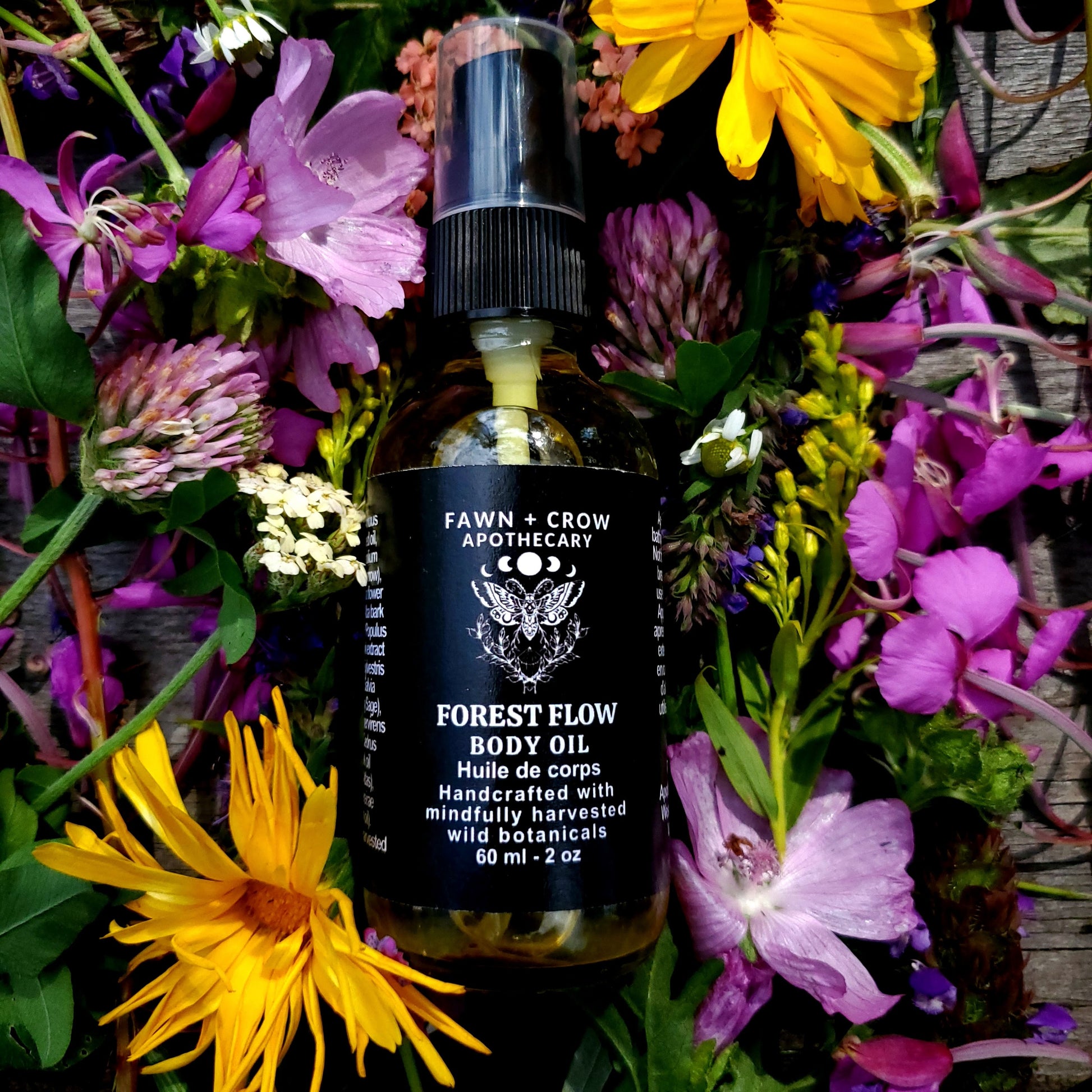 Body oil bottle labeled 'Forest Flow' surrounded by colorful flowers