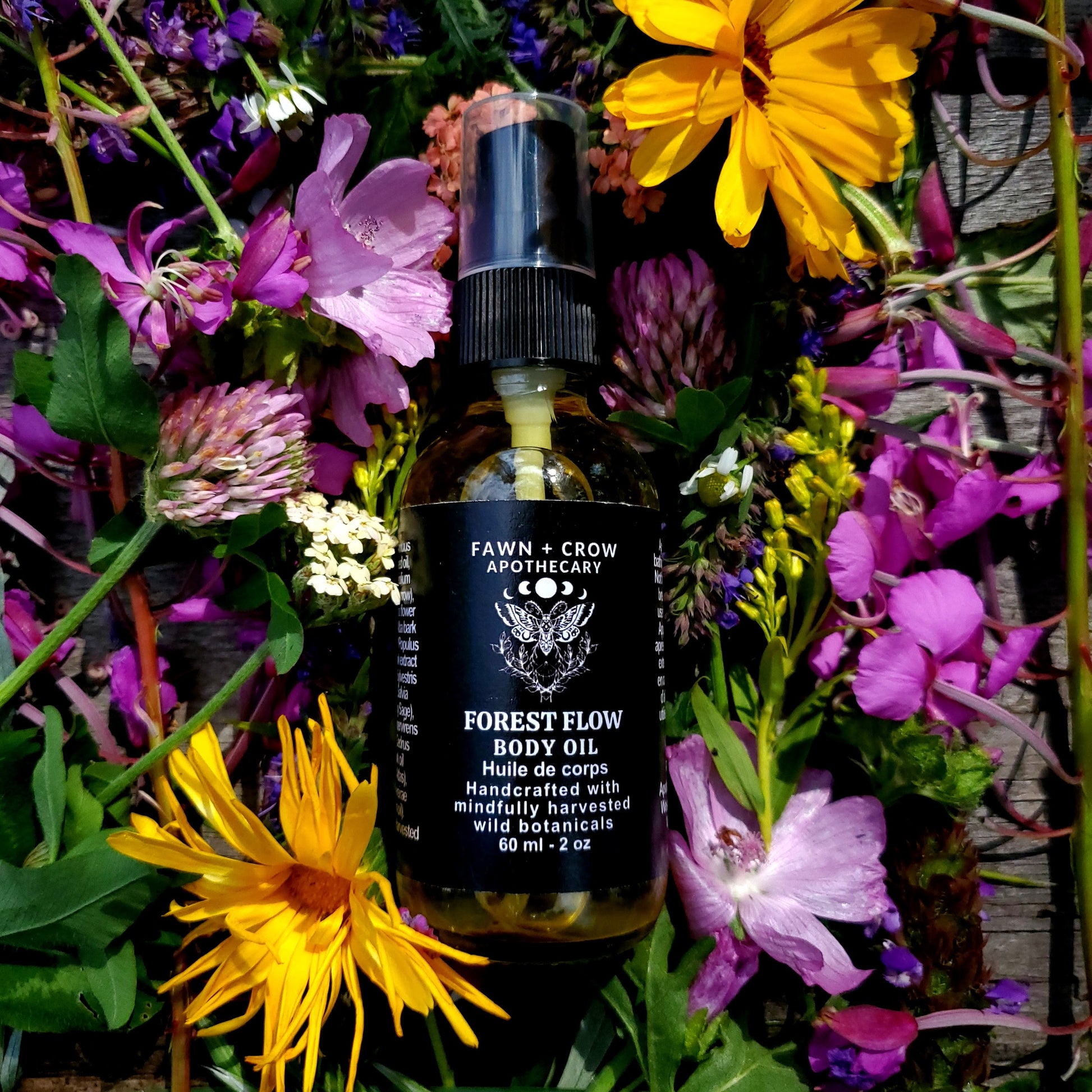 Bottle of Fawn & Crow Apothecary Forest Flow Body Oil surrounded by wildflowers