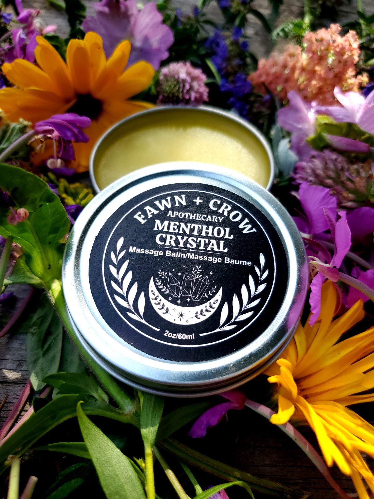Fawn and Crow Apothecary Menthol Crystal balm tin surrounded by flowers