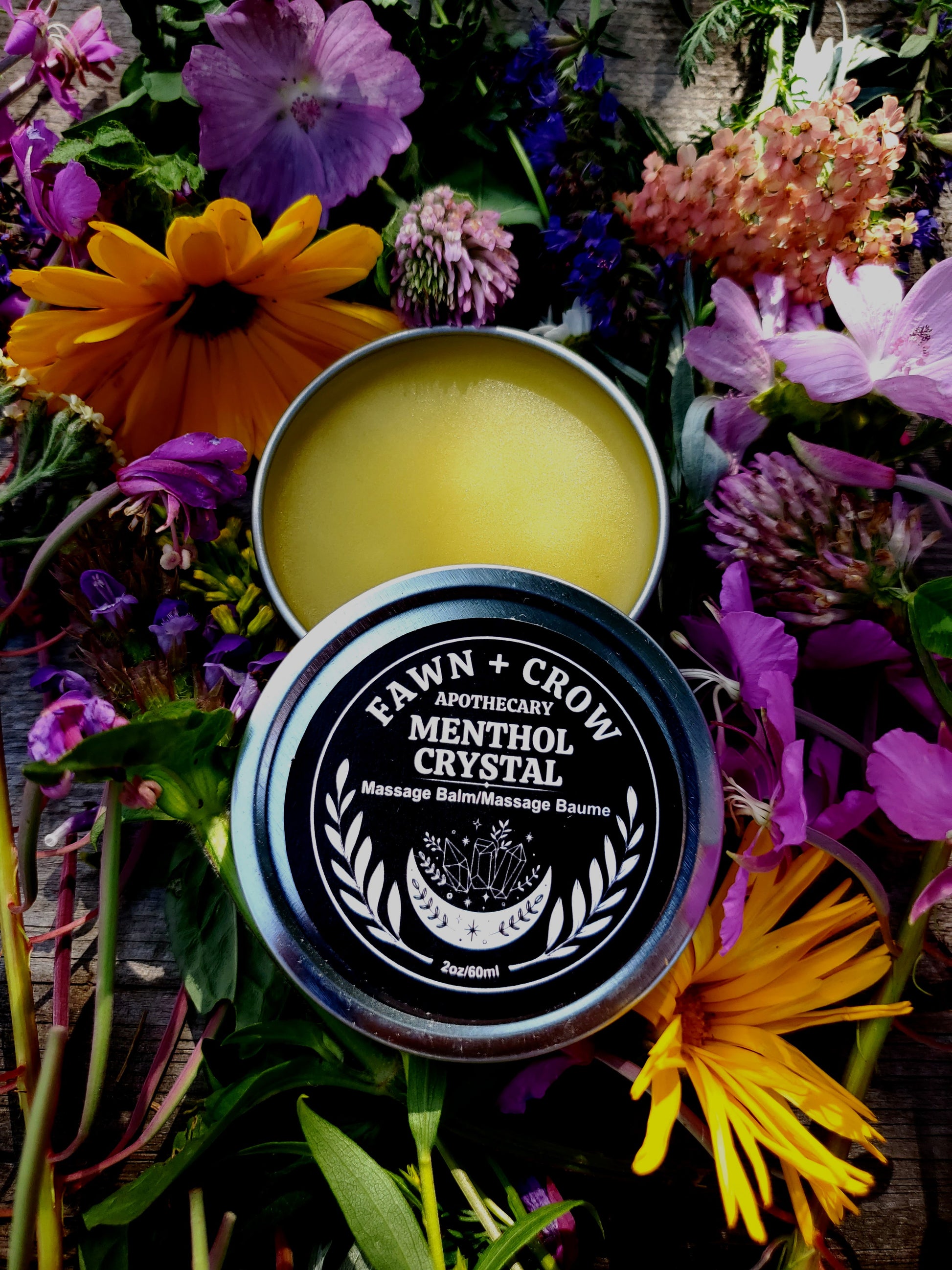 Tin of Fawn & Crow Menthol Crystal Massage Balm surrounded by flowers