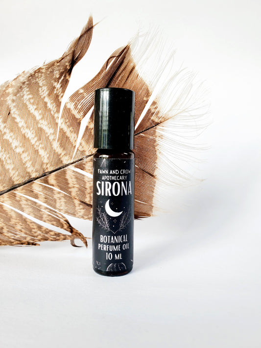 Sirona ritual perfume oil bottle with feathers behind
