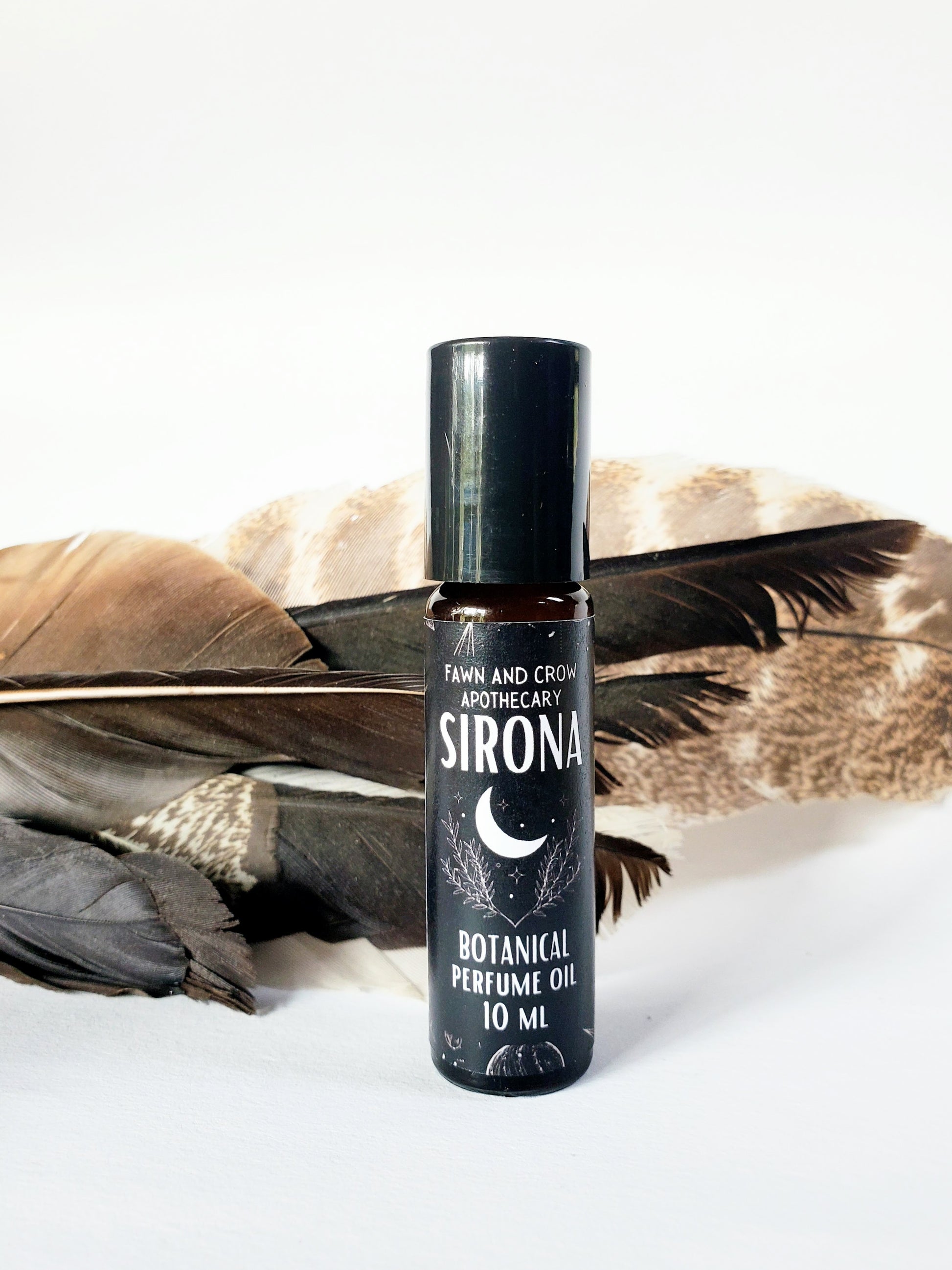 Sirona ritual perfume oil bottle with feathers in background