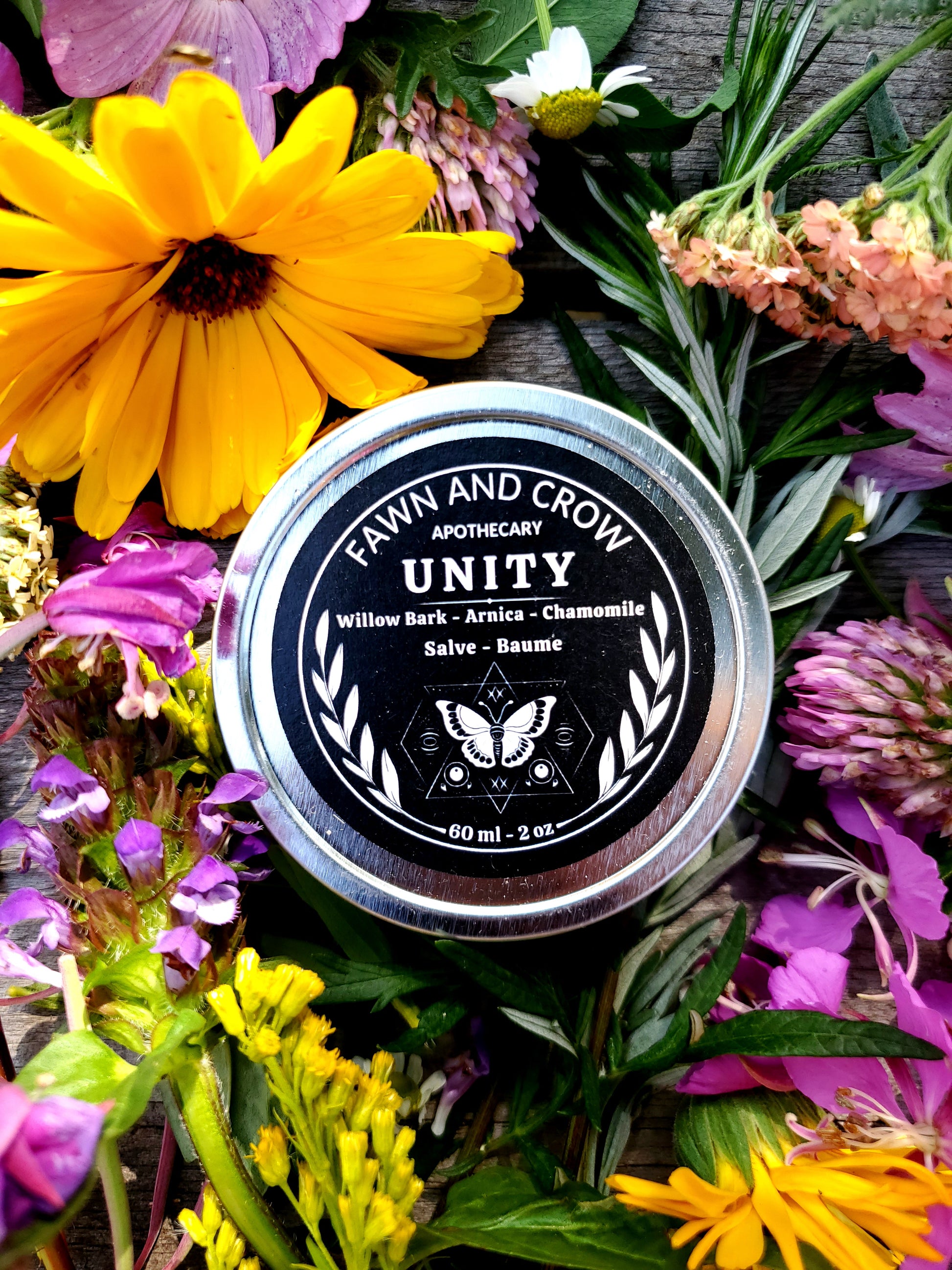 Jar of Farm and Crow Unity salve surrounded by colorful flowers