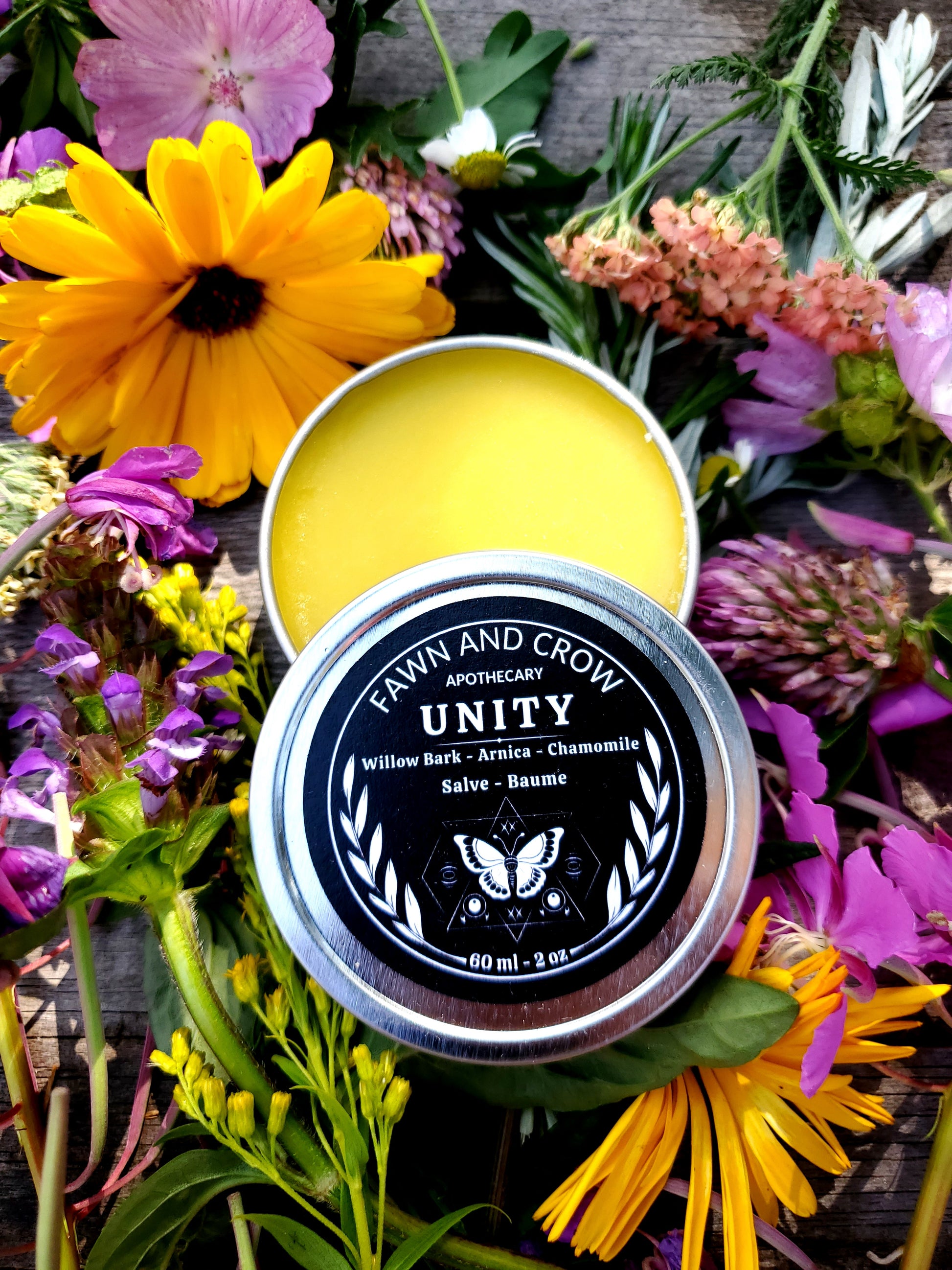Yellow balm in a silver tin with 'Unity' branding surrounded by colorful flowers