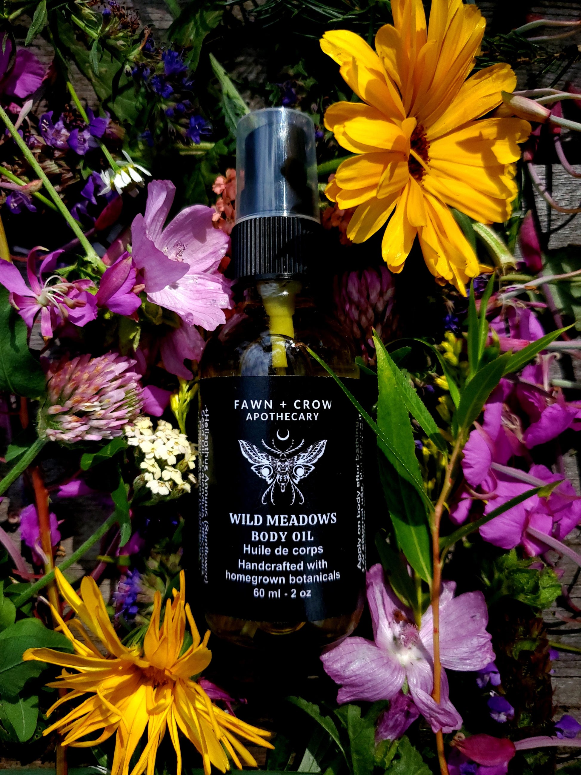 Bottle of Fawn & Crow Apothecary body oil surrounded by wildflowers