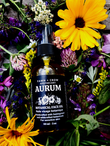 Bottle of Fawn + Crow Apothecary Aurum Botanical Face Oil surrounded by flowers on a wooden surface