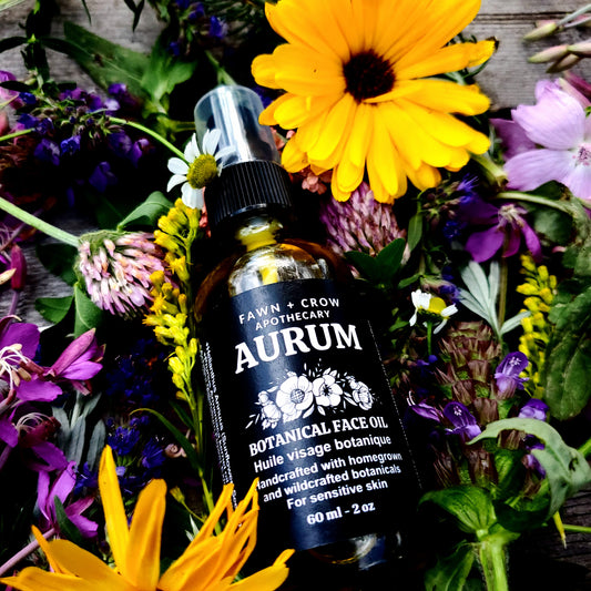 Aurum botanical face oil bottle surrounded by wildflowers on a wooden surface