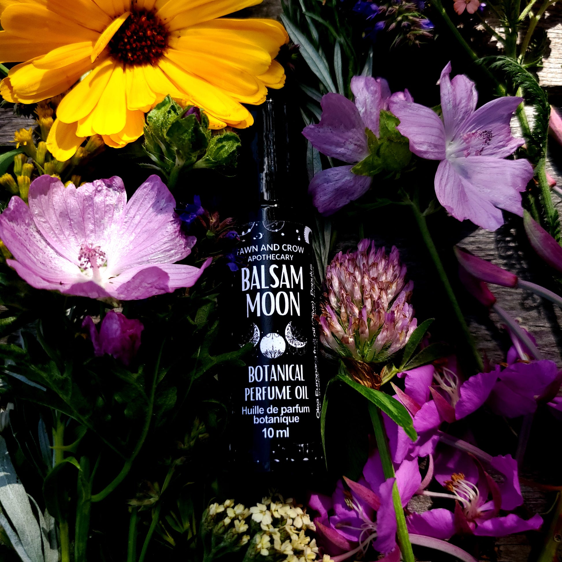 Balsam of the Moon perfume bottle surrounded by flowers