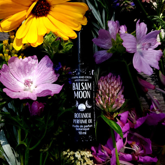 Bottle of Balsam Moon Perfume Oil surrounded by purple and yellow flowers