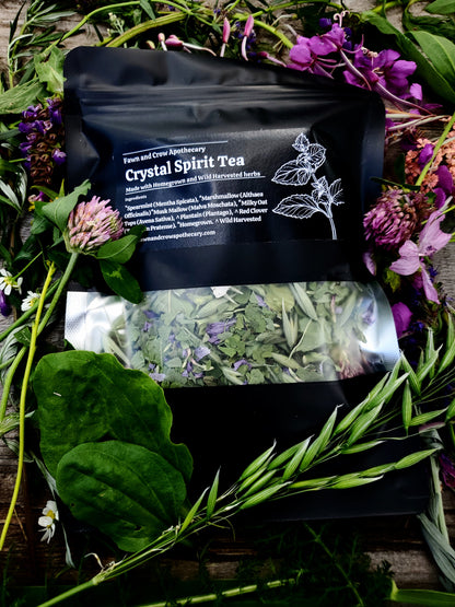 Crystal Spirit Tea package surrounded by herbs and flowers on a wooden surface