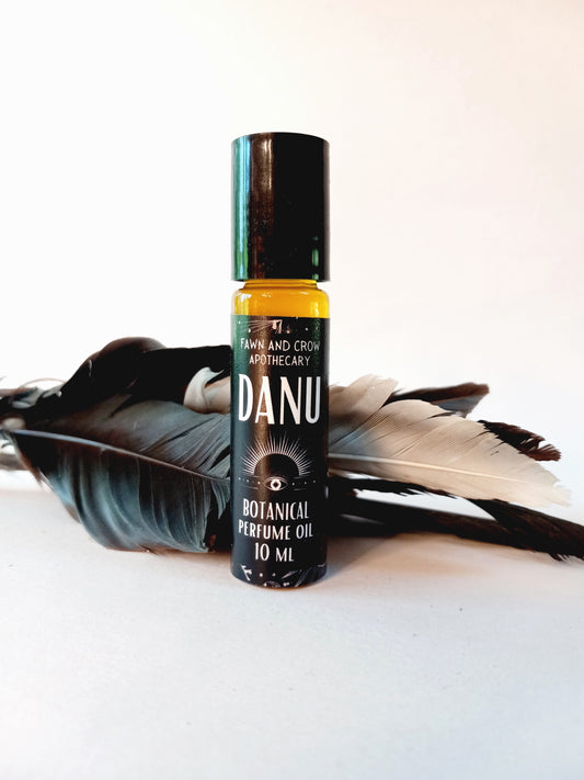 Danu botanical perfume oil with feathers behind small bottle