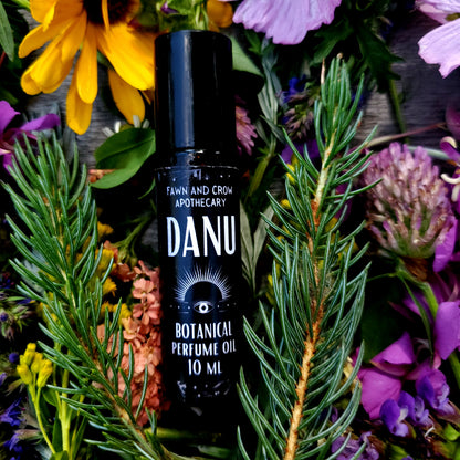 DANU perfume oil bottle surrounded by flowers and greenery