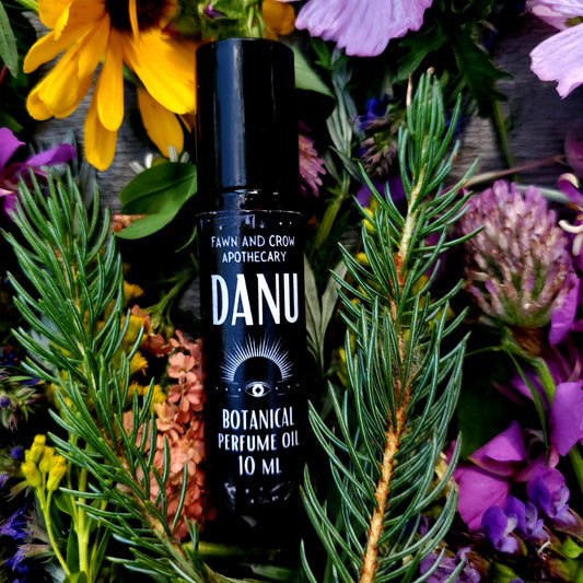 DANU perfume oil bottle surrounded by flowers and greenery