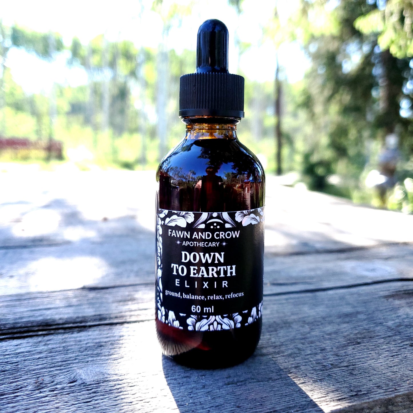 Bottle of 'Down to Earth Elixir' by Fawn and Grow on a wooden surface with blurred natural background
