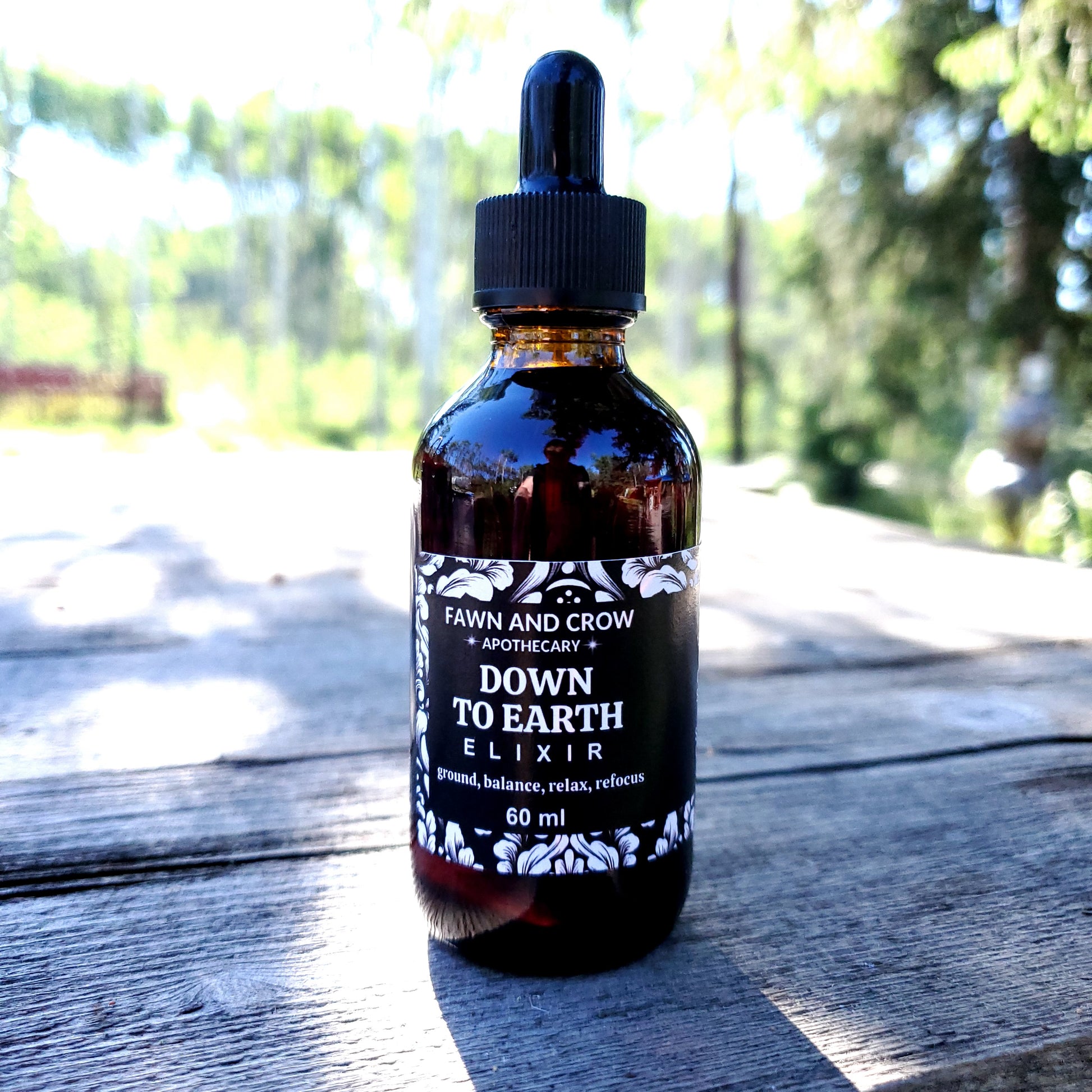 Bottle of 'Down to Earth Elixir' by Fawn and Grow on a wooden surface with blurred natural background