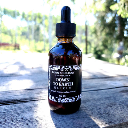 Bottle of 'Down to Earth Elixir' by Fawn and Grow on a wooden surface with blurred natural background