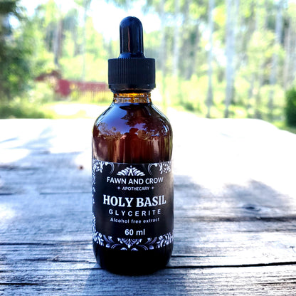 Bottle of Fawn and Crow Apothecary Holy Basil Glycerite on a wooden surface with a blurred natural background