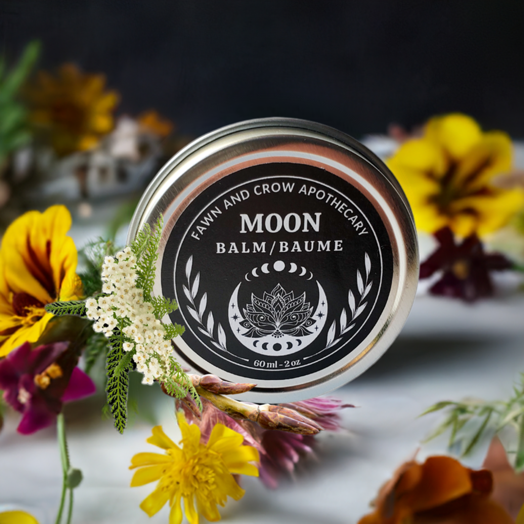 Mentrual cycle botanical pain relief balm in silver tin surrounded by flowers 