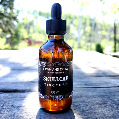 Skullcap tincture bottle on a wooden surface with blurred greenery in the background