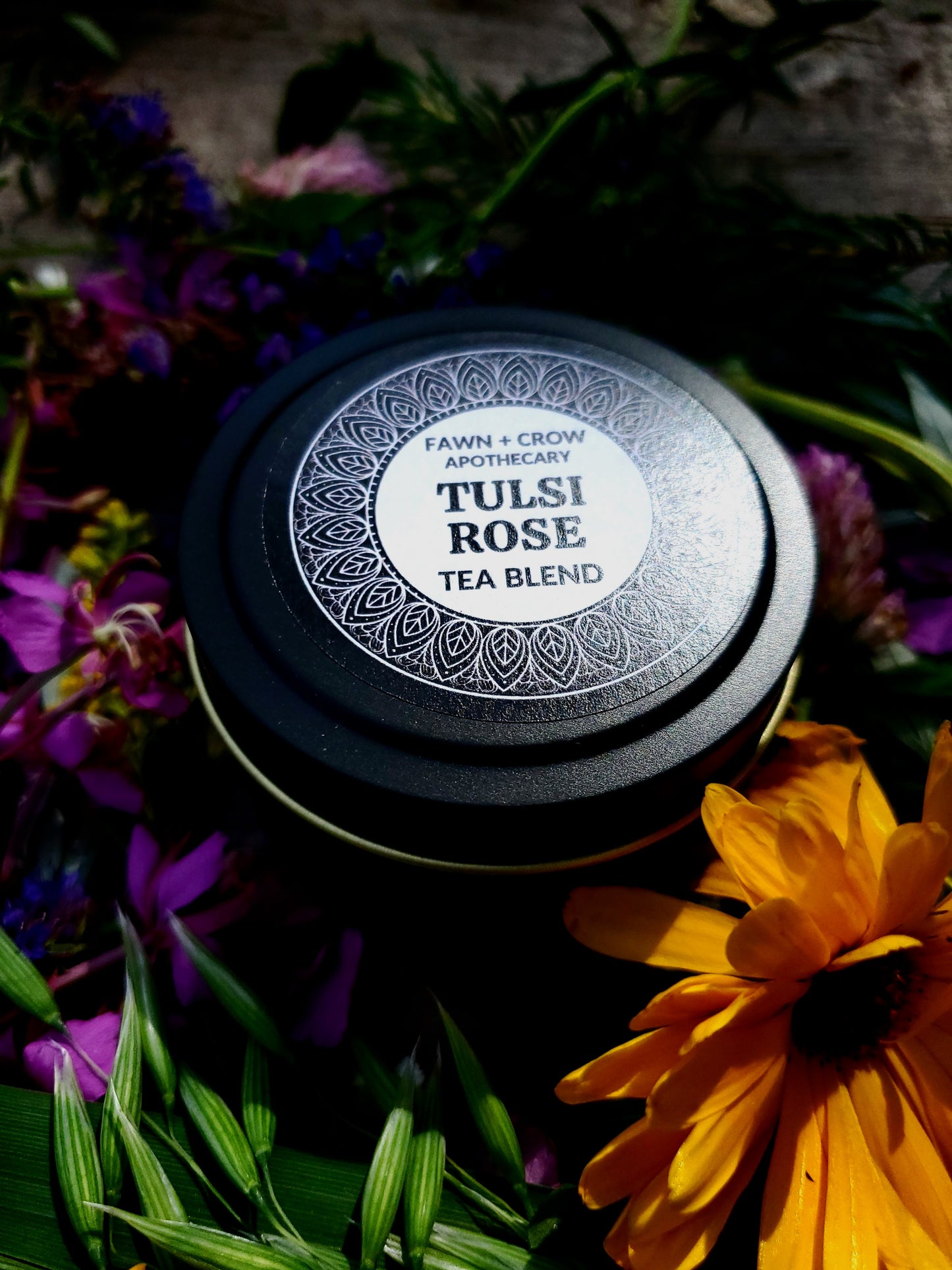 Tulsi Rose tea blend container surrounded by flowers and greenery